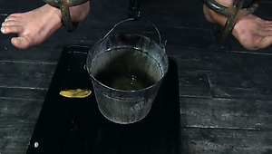 Chubby brunette teen pisses in bucket being suspended in metal cage